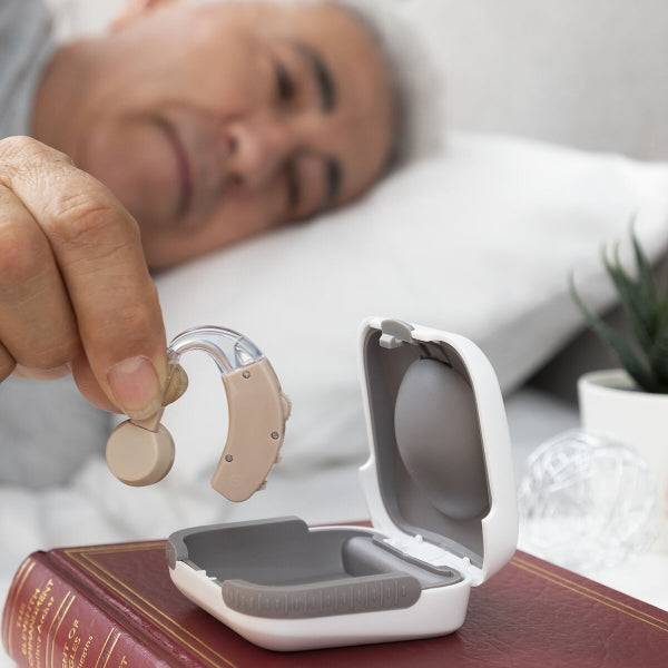 Bărbat așezat în pat depozitează dispozitivul audio portabil Welzy în husa sa, evidențiind portabilitatea și ușurința în utilizare