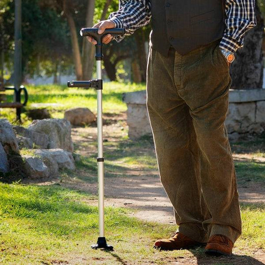Baston Extensibil cu LED, Alarmă și Mână Mecanică – Hannde Inovamarket folosit de un bărbat în parc, oferind sprijin stabil pe teren denivelat